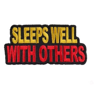 May include: Black embroidered patch with the text "Sleeps Well With Others" in yellow and red lettering.