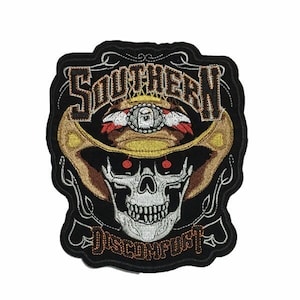 May include: Black and white embroidered patch with a skull wearing a cowboy hat. The hat has a gold band and a red, white, and blue band. The text "Southern Discomfort" is embroidered below the skull.