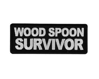 May include: Black embroidered patch with white text that reads "WOOD SPOON SURVIVOR".