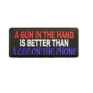 May include: Black rectangular patch with embroidered text in red, white, and blue. The text reads: "A GUN IN THE HAND IS BETTER THAN A COP ON THE PHONE."