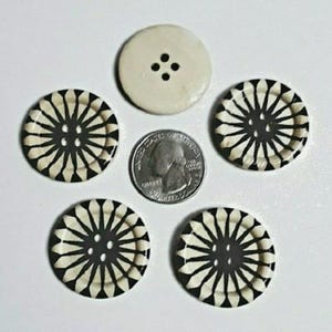 May include: Five buttons with a black and white geometric design. One button is plain white with four black dots.