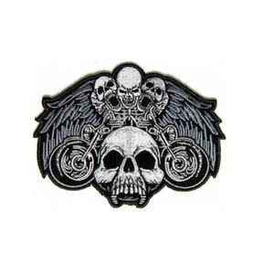 May include: Black and white embroidered patch featuring a skull with wings and a motorcycle. The skull has three smaller skulls on top of its head.