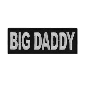 May include: Black rectangular patch with the embroidered text "BIG DADDY" in white block letters. The patch is likely designed to be sewn or ironed onto clothing or accessories.