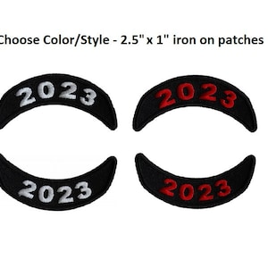 May include: Four iron-on patches with the year 2023 in white and red lettering on a black background. The patches are 2.5 inches by 1 inch.