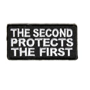 May include: Black and white embroidered patch with the text "The Second Protects The First".