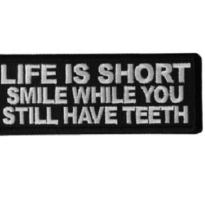 May include: Black and white embroidered patch with the text "Life is short smile while you still have teeth".