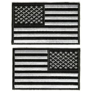 May include: Two black and white embroidered American flag patches. The flags are sewn with white thread on a black fabric background.