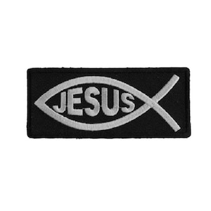 May include: A black fabric patch with a white embroidered Jesus fish symbol. The fish has the word "JESUS" inside.