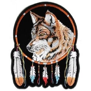 May include: Embroidered patch featuring a wolf's head inside a dreamcatcher with feathers and beads. The wolf is brown, white, and gray, and the dreamcatcher is brown, orange, and white.