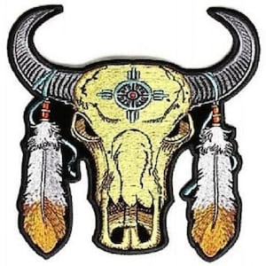 May include: Embroidered patch featuring a yellow and black buffalo skull with a turquoise and red Native American symbol on the forehead. Two white and orange feathers hang from the sides of the skull.