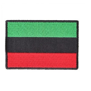 May include: A green, black, and red embroidered patch. The patch is rectangular and has a stitched border.