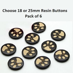 May include: A pack of six black resin buttons with a paw print design. The buttons are 25mm in diameter and are ideal for crafting projects.