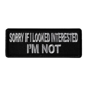 May include: Black embroidered patch with white text that reads "Sorry if I looked interested I'm not".