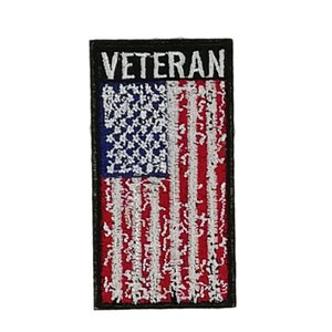 May include: A black and white embroidered patch with a distressed American flag and the word "Veteran" in white lettering.