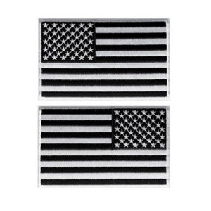 May include: Two black and white embroidered American flag patches. The flags are sewn on a white background.