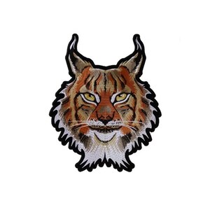 May include: Embroidered patch of a lynx's face with brown, orange, and white fur. The lynx has yellow eyes and a black outline.