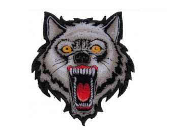 May include: A close-up of a snarling wolf's head with a black outline and white fur. The wolf's eyes are yellow, and its mouth is open, revealing sharp teeth and a red tongue.