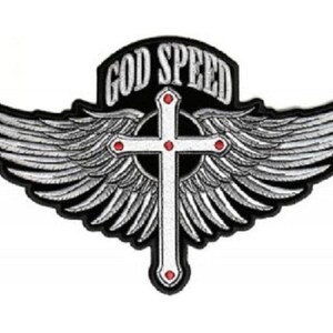 May include: A black and white embroidered patch with a white cross and silver wings. The text "GOD SPEED" is written in a black banner above the cross.