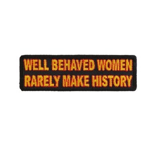 May include: Black rectangular patch with the text "WELL BEHAVED WOMEN RARELY MAKE HISTORY" in yellow and orange thread. The patch has a black border and is set against a white background.