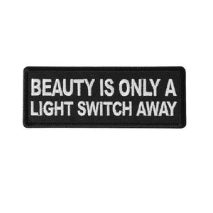 May include: Black embroidered patch with white text that reads "BEAUTY IS ONLY A LIGHT SWITCH AWAY".