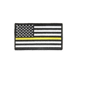 May include: A black and white American flag patch with a yellow stripe across the middle. The patch is embroidered and has a black border.