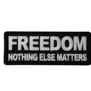 May include: Black rectangular patch with white embroidered text. The word "FREEDOM" is at the top, with "NOTHING ELSE MATTERS" below it. The patch has a black border and is set against a white background.