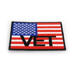 May include: A red, white, and blue American flag patch with the word "VET" embroidered in black.