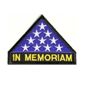 May include: A blue and white triangular patch with 13 white stars and the text "IN MEMORIAM" in yellow letters on a black background.