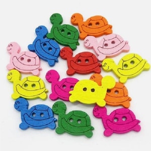 May include: A collection of colorful wooden turtle-shaped buttons in various shades, including green, blue, pink, yellow, orange, and red. Each button has two holes for sewing and a detailed turtle shell design.