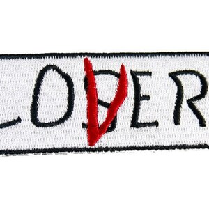 May include: White embroidered patch with black lettering that reads "LOVER" with a red "V" in the center.