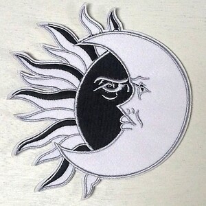May include: Embroidered patch featuring a celestial design of a sun and moon. The sun's rays and the moon's crescent are white, with black accents. The moon's face is half black and half white, with detailed facial features.