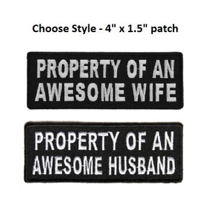 May include: Two black iron-on patches with white text. The top patch reads "PROPERTY OF AN AWESOME WIFE". The bottom patch reads "PROPERTY OF AN AWESOME HUSBAND".