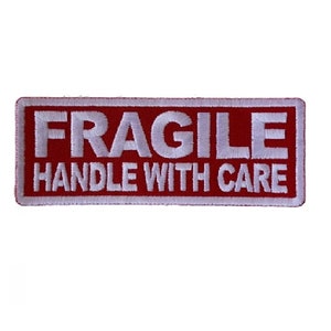 May include: Red rectangular patch with white embroidered text that reads "FRAGILE HANDLE WITH CARE".