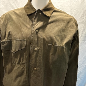 Puede incluir: Una camisa verde de manga larga con botones, dos bolsillos de solapa y cuello de pana.