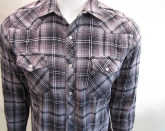 May include: A long-sleeved plaid shirt with a button-down front and two chest pockets. The shirt is a mix of black, white, and gray.