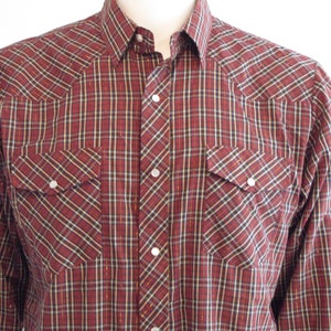 May include: A red and black plaid long-sleeve shirt with pearl-like buttons and two chest pockets.