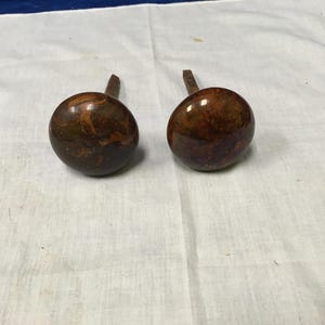 May include: Two brown ceramic door knobs with a marbled pattern and metal stems.