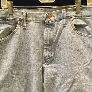 May include: Light blue denim jeans with a button fly and two front pockets. The jeans have a faded look and are made of a soft, comfortable material.