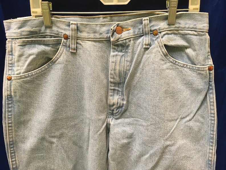 May include: Light blue denim jeans with a button fly and two front pockets. The jeans have a faded look and are made of a soft, comfortable material.
