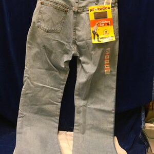 May include: Light blue denim jeans with a Wrangler Pro Rodeo Cowboy Cut label. The label features a cartoon cowboy and the text "Cowboy Cut" and "Wrangler".