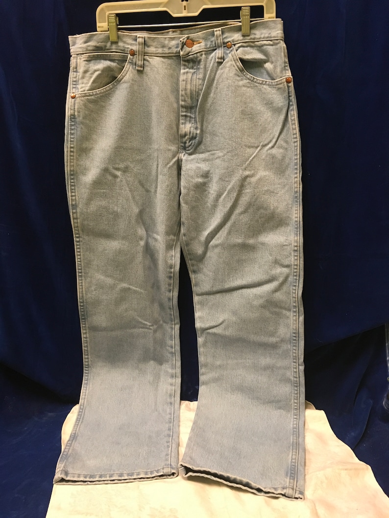 May include: Light blue denim jeans with a straight leg and a slight flare at the bottom. The jeans have a button fly and five pockets.