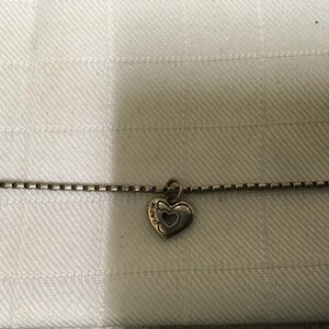 May include: Silver necklace featuring a heart pendant. The pendant has a heart outline with a smaller heart inside. The word "LOVE" is inscribed on the pendant. The chain is a box chain style.