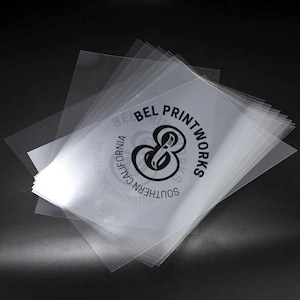 May include: A stack of clear plastic sheets with a black logo that says "Southern California Bel Printworks" with a stylized ampersand symbol.