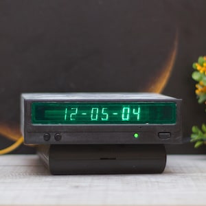 May include: A black digital clock with a green display showing the date "12-05-04".