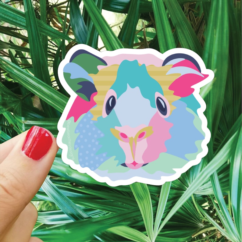 Puede incluir: Una pegatina colorida de la cara de un conejillo de indias con un dise&ntilde;o de patchwork en tonos de rosa, azul, verde y amarillo.