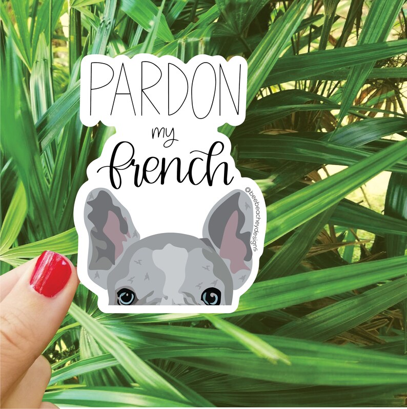 May include: A white sticker with the text "Pardon my french" in black cursive lettering. A cartoon image of a French bulldog's face peeks out from behind the text. The bulldog has gray fur and blue eyes.