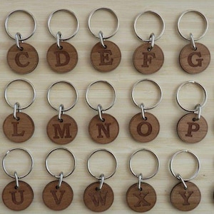 May include: Twenty-six wooden keyrings with silver key rings, each featuring a different letter of the alphabet.