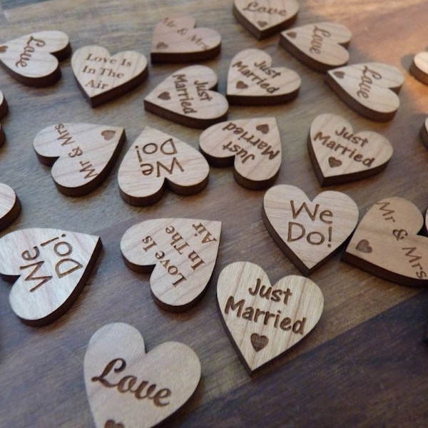 May include: Wooden heart-shaped wedding favors with various sayings, including "We Do!" "Just Married" and "Love Is In The Air".