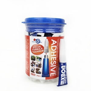 以下が含まれることがあります： シアンアクリレート接着剤の小さなチューブが25本入った透明なプラスチック製の瓶。瓶は青い蓋と、赤と白のラベルが付いており、「Special Formula for Aquarium」と書かれている。ラベルには、植物と岩のある水槽の画像も描かれている。チューブには「Super Glue」と「Mixbon」のラベルが貼られている。