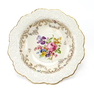 以下が含まれることがあります： 金色の縁取りと複雑な花柄が施された白い磁器のボウル。ボウルには、ピンク、紫、黄色の花と緑の葉のブーケが描かれている。